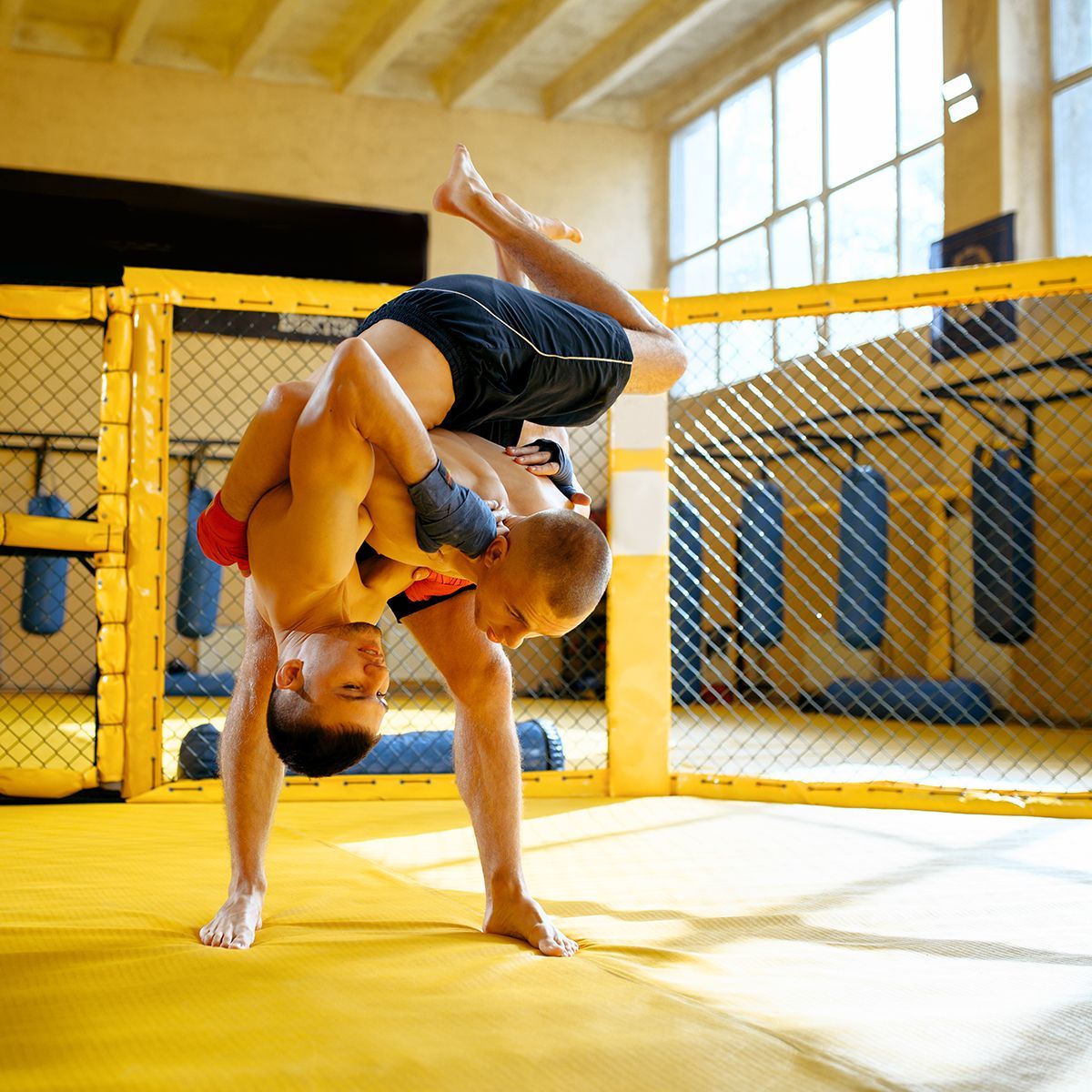 Two men are wrestling in a cage and one is doing a handstand