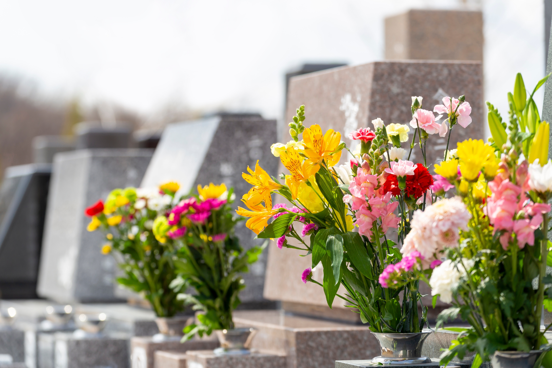 A row of vases filled with flowers in a cemetery.