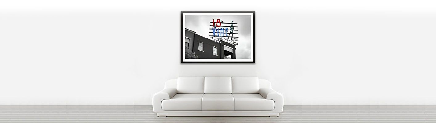 White sofa under a framed artwork on a white wall.