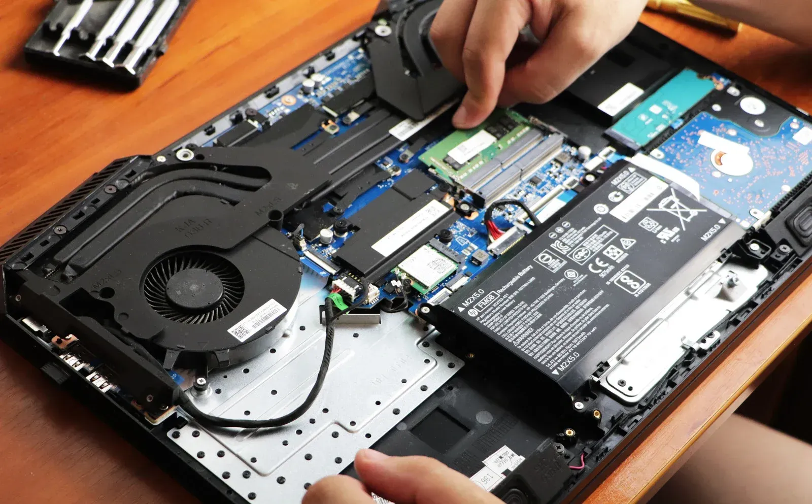 A person is working on a laptop computer on a wooden table.