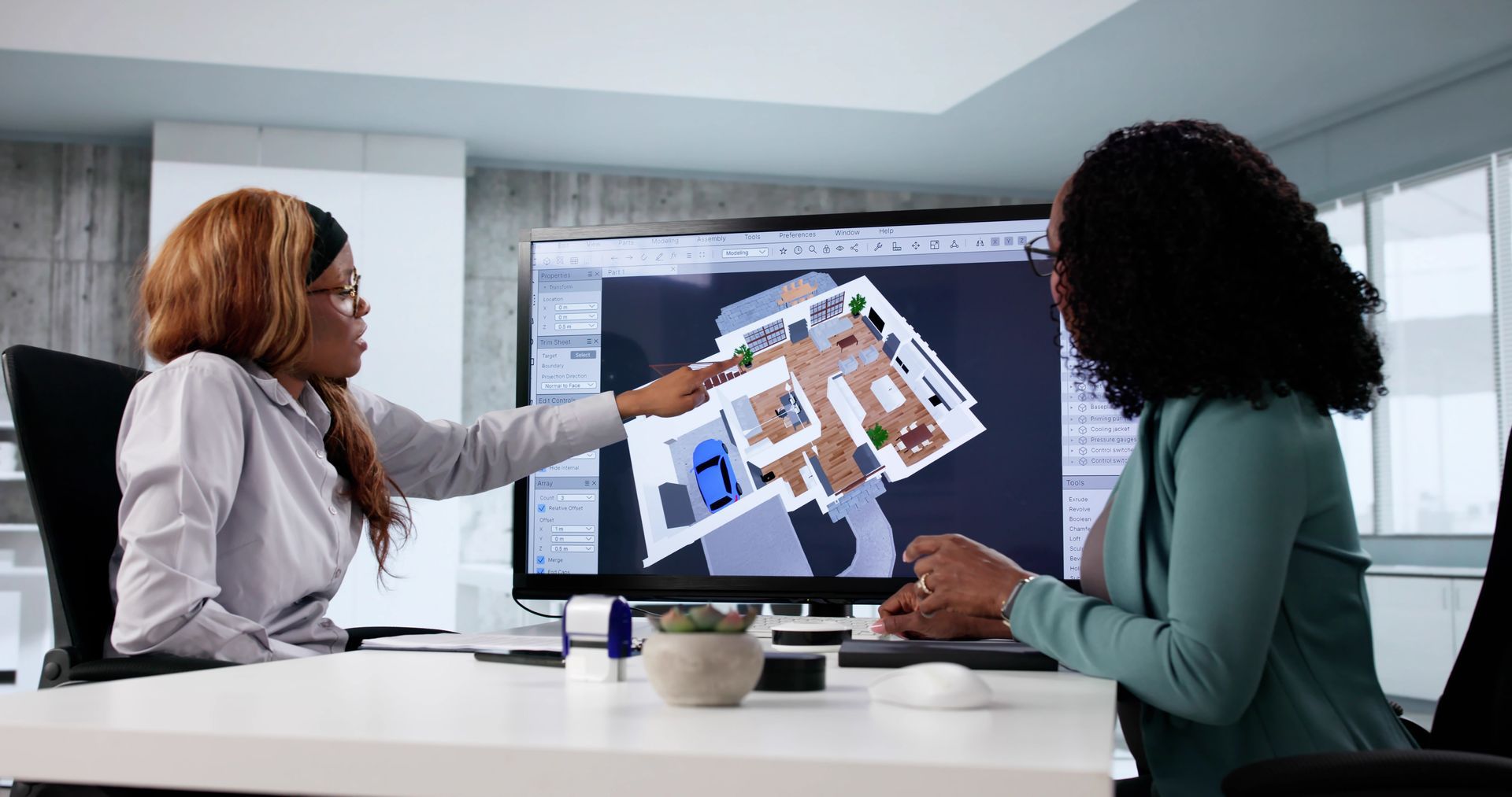 Deux personnes regardent un plan de maison sur un écran d'ordinateur, l'une le pointant du doigt.