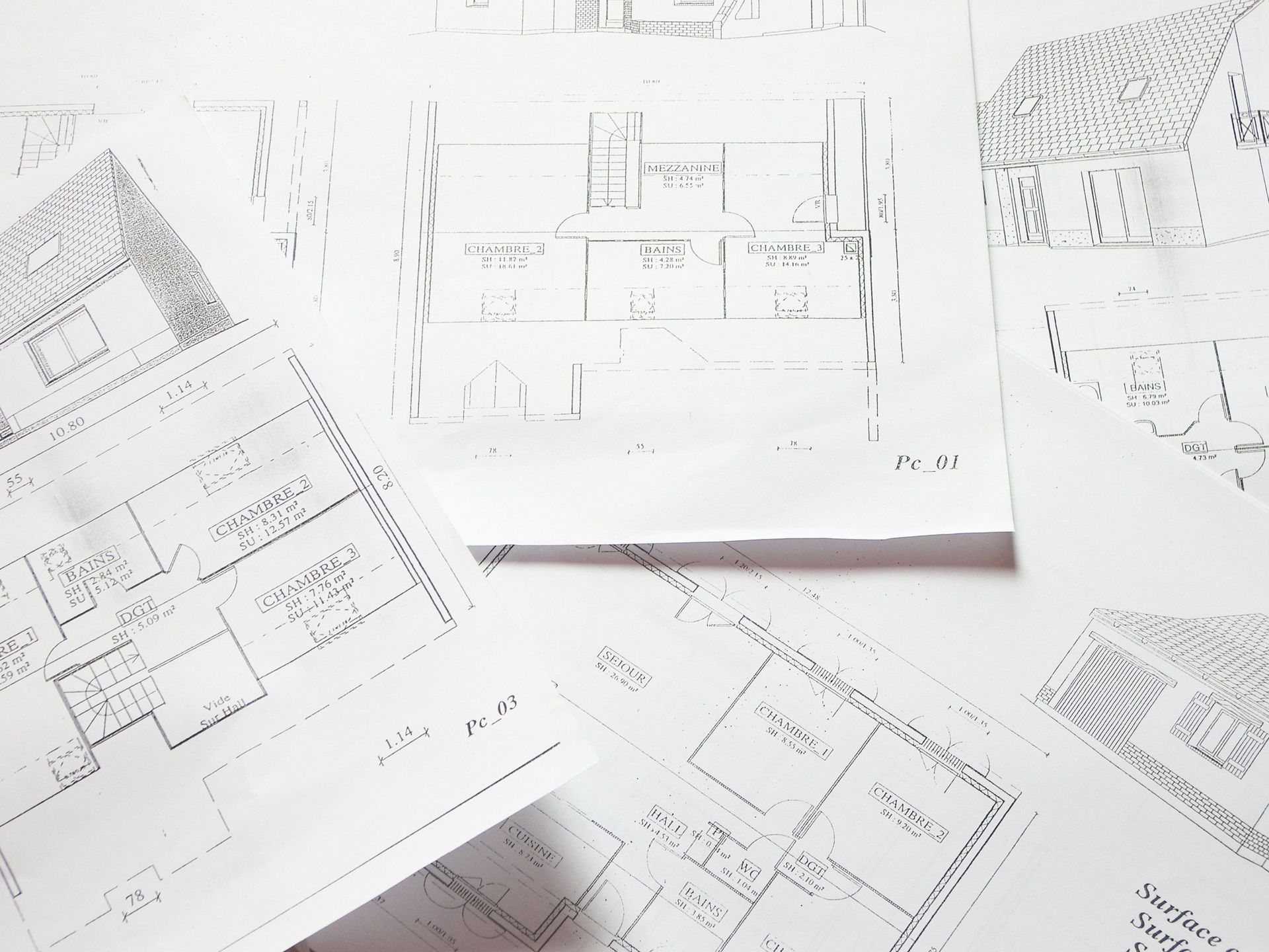Un tas de dessins d'une maison sont posés sur une table