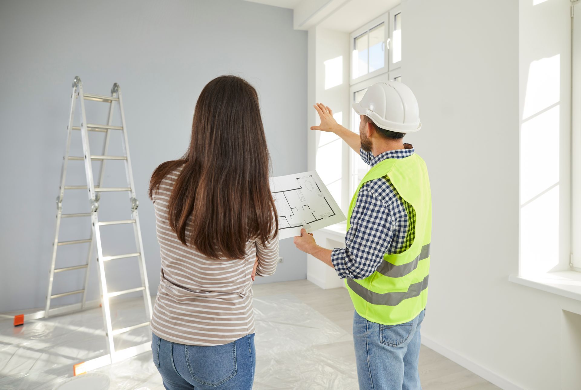 Un homme et une femme regardent un plan dans une pièce.