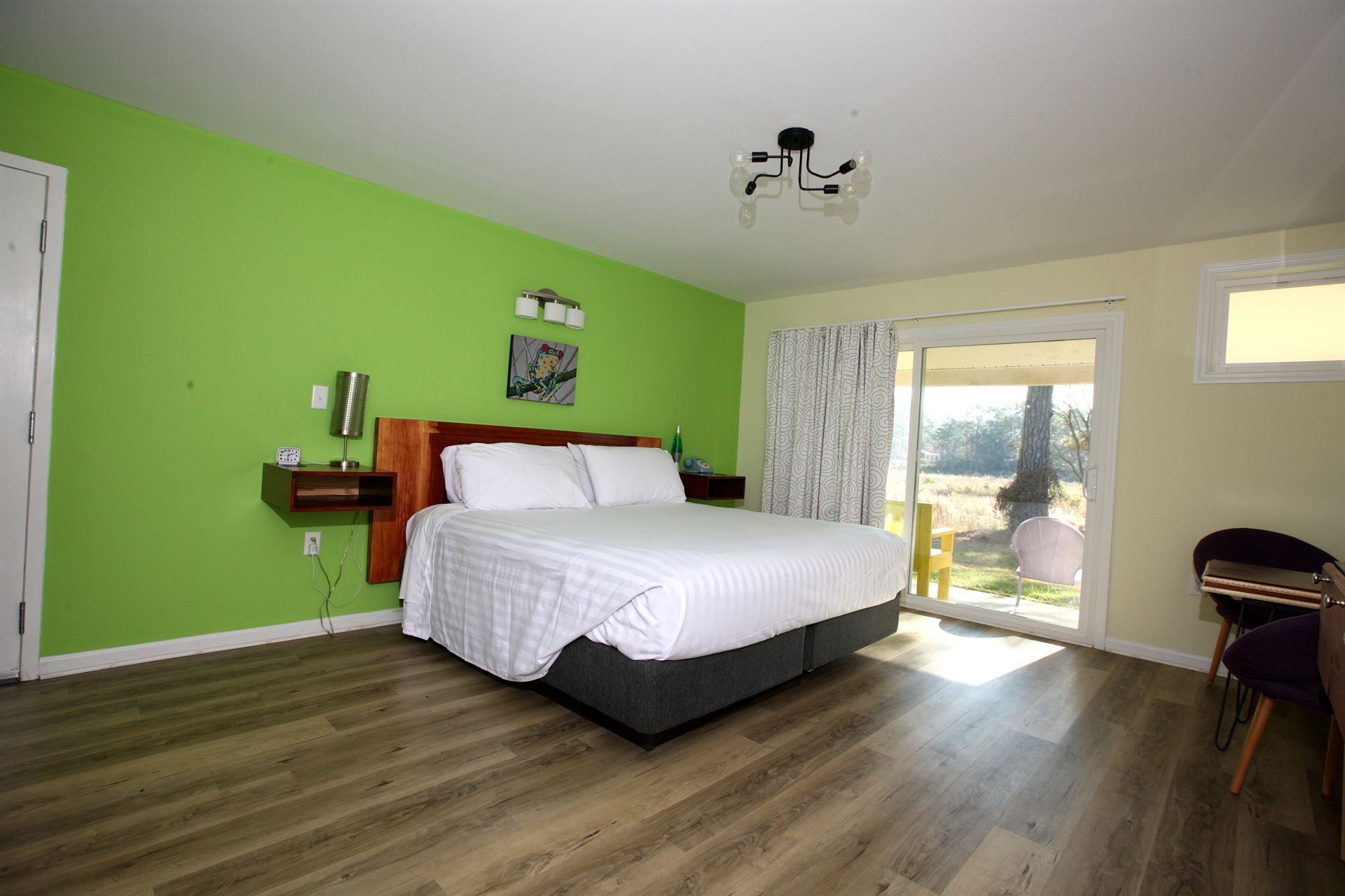 A hotel room with a king size bed and green walls.