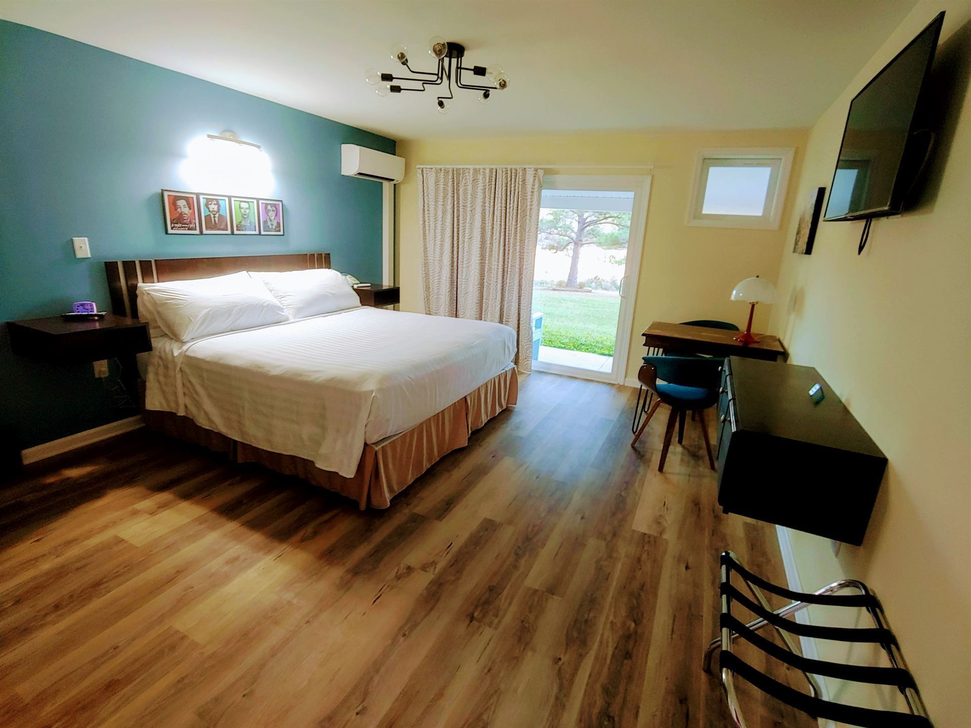 A hotel room with a king size bed , desk and television.