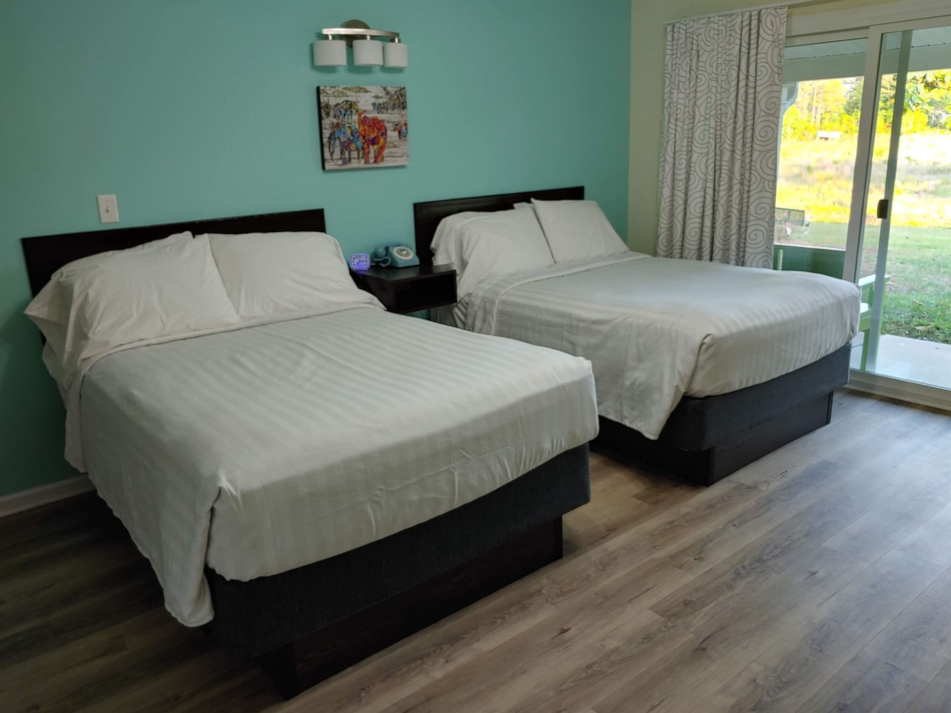 A hotel room with two beds and a sliding glass door.