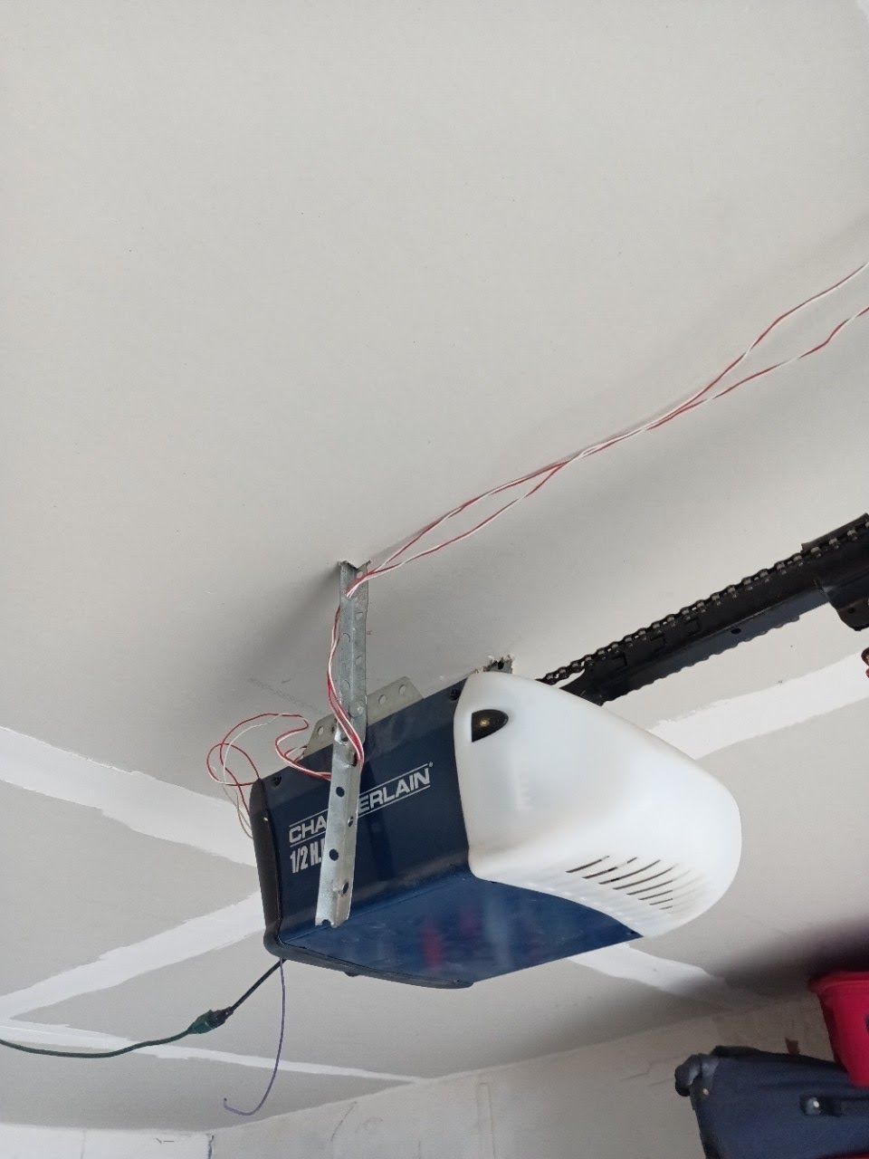 Garage door opener mounted on a white ceiling with exposed wiring.