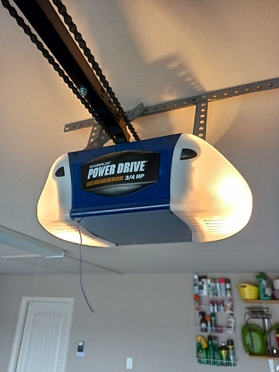 Garage door opener mounted on ceiling with chain drive.