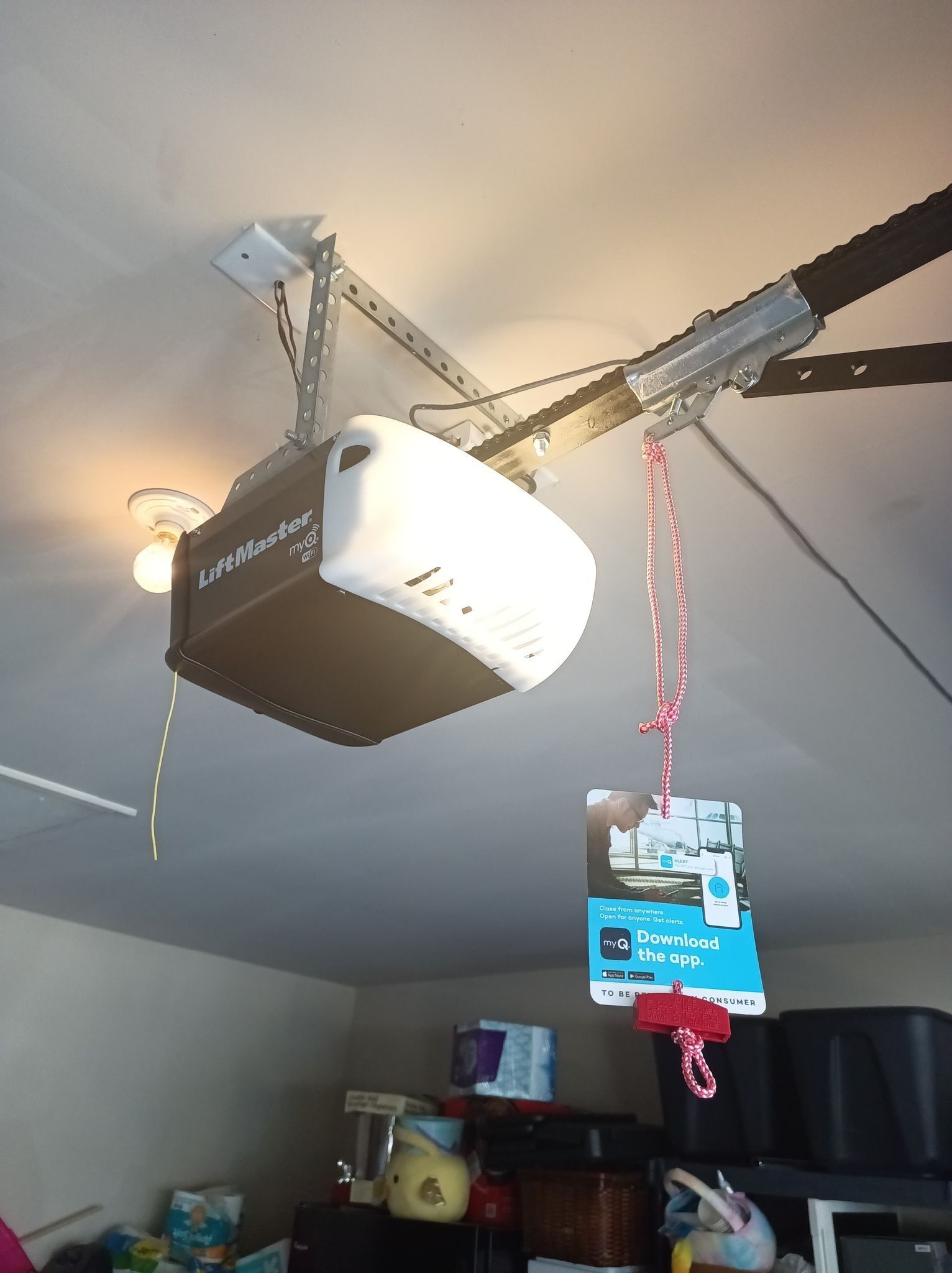 Garage door opener mounted on ceiling, with attached tag hanging down.