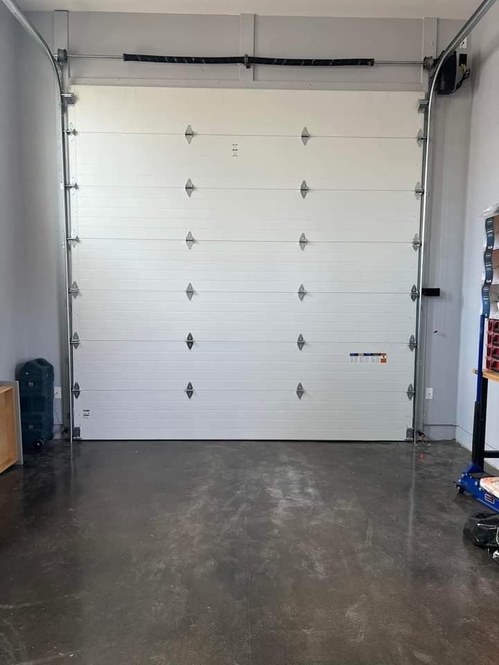 White garage door, closed, in a garage with a concrete floor.