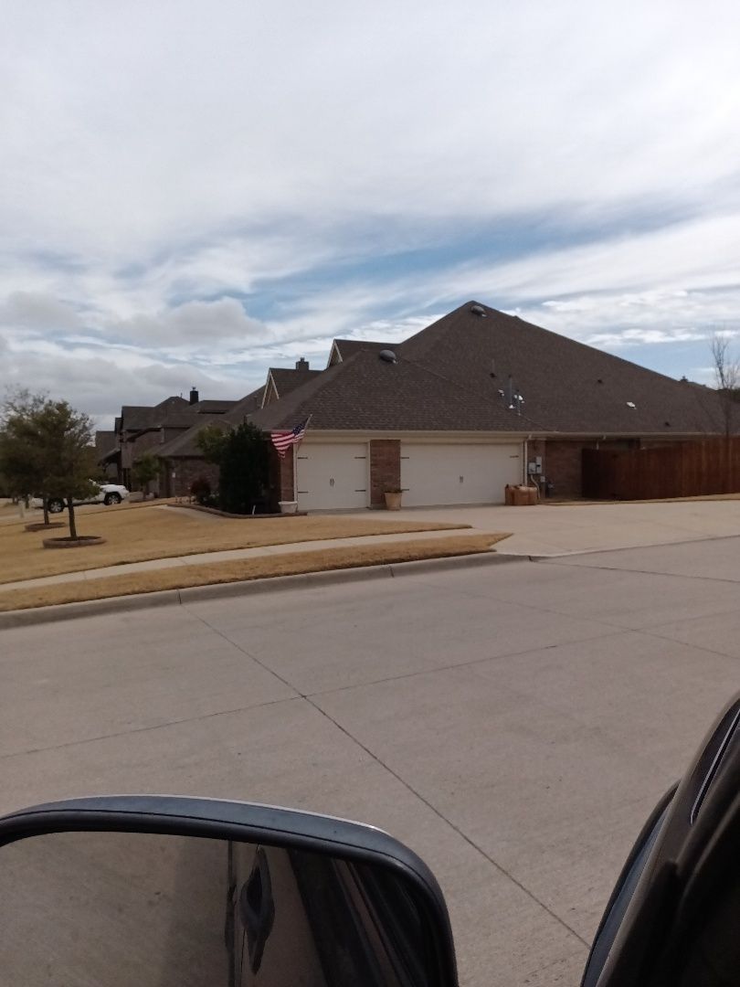 Residential street with houses. Two-car garage, brown roof, and cloudy sky.