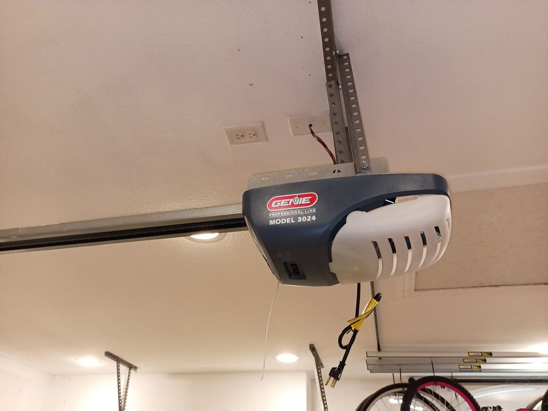 Garage door opener mounted on the ceiling; a Genie model in blue and white.