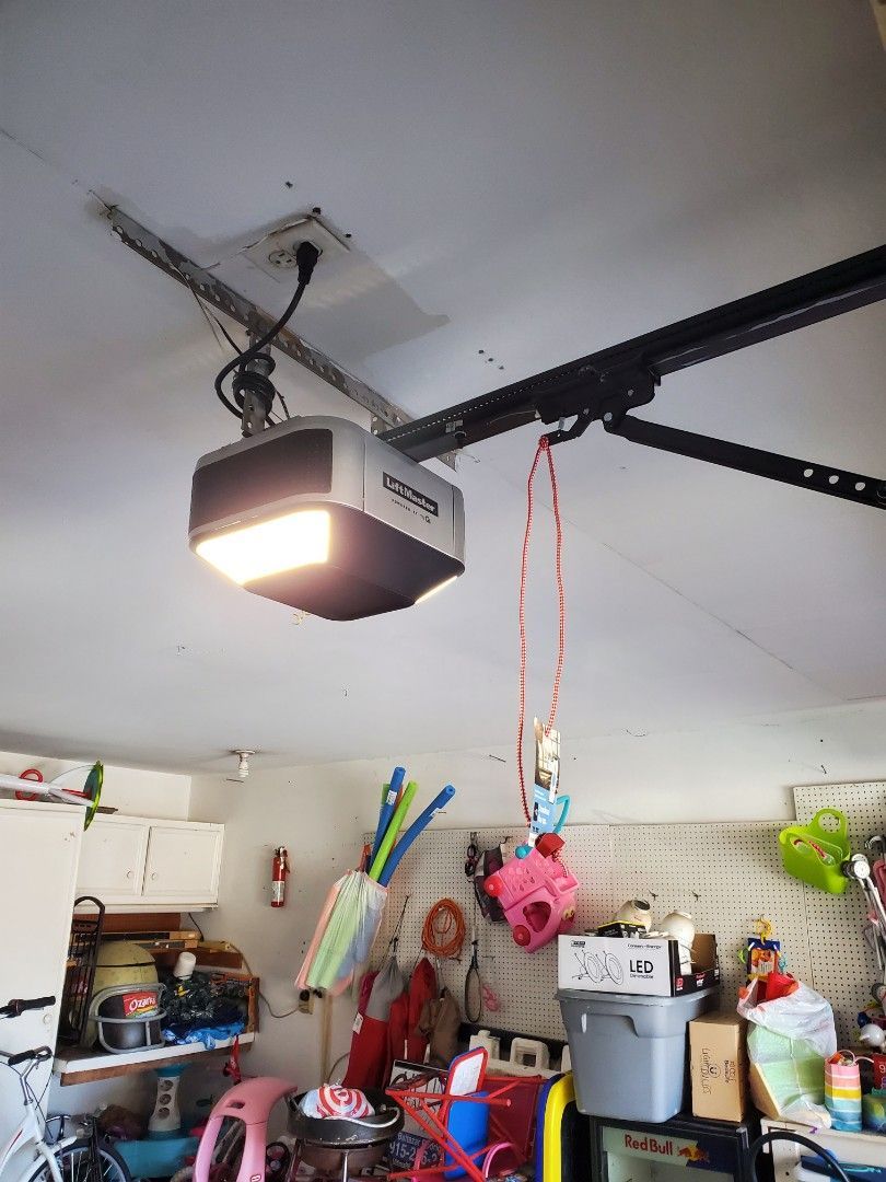 Garage ceiling with garage door opener and various hanging items.