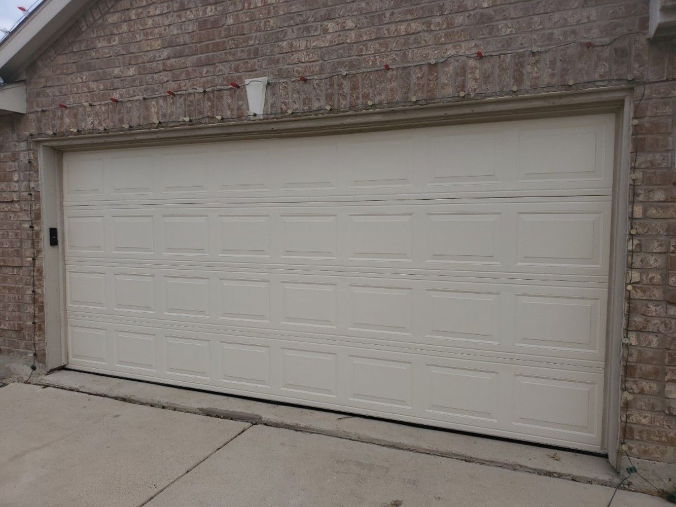 Closed cream-colored garage door in brick-walled structure.