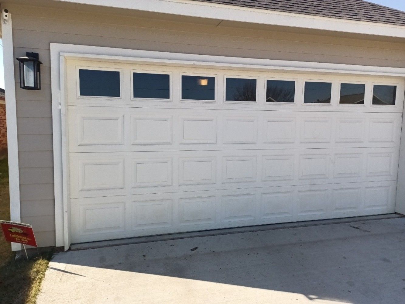 White garage door with multiple small windows, mounted on a tan house.
