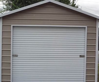 Tan and white metal garage with a closed, gray roll-up door.