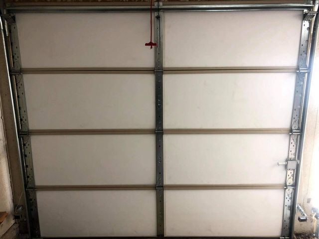 Interior of a white garage door with metal frame and horizontal sections. A red pull cord hangs from the top.
