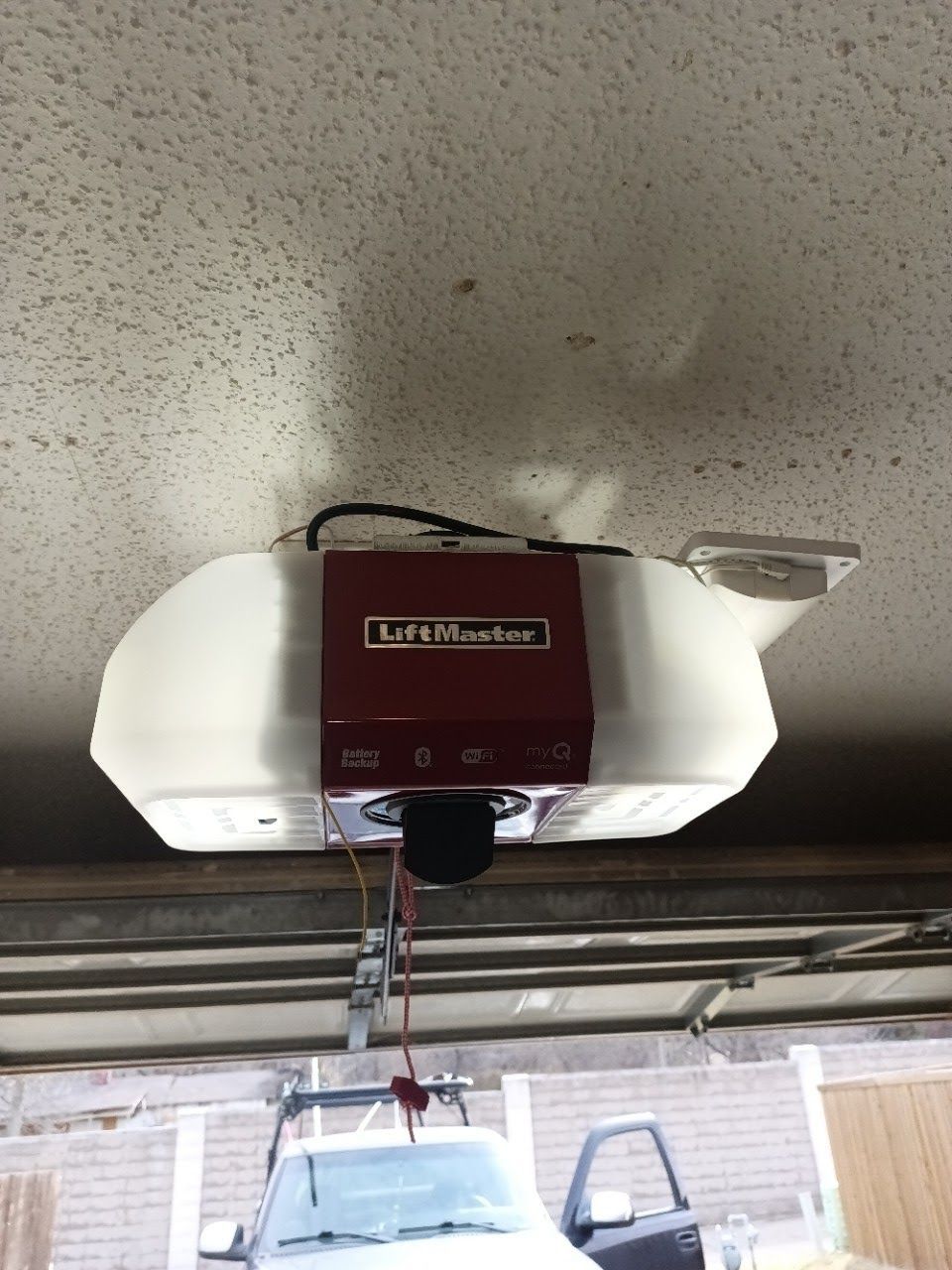 LiftMaster garage door opener mounted on a white ceiling; a truck is visible below.