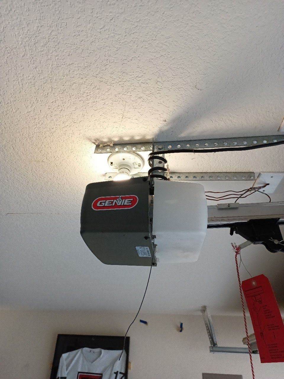 A Genie garage door opener mounted on a white ceiling.