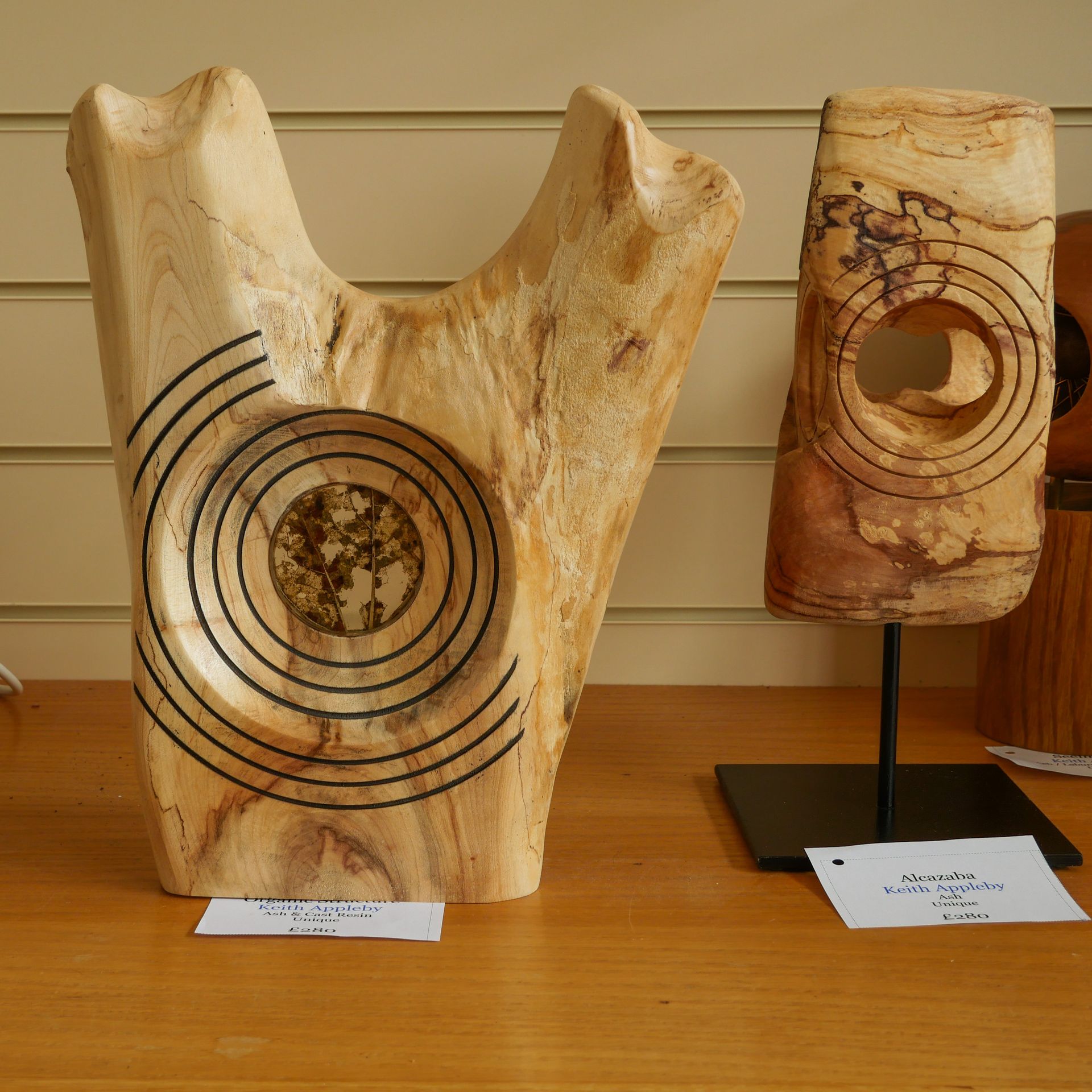 Two wooden sculptures are sitting on a wooden table