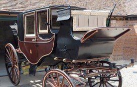 A horse drawn carriage is parked in front of a brick building.