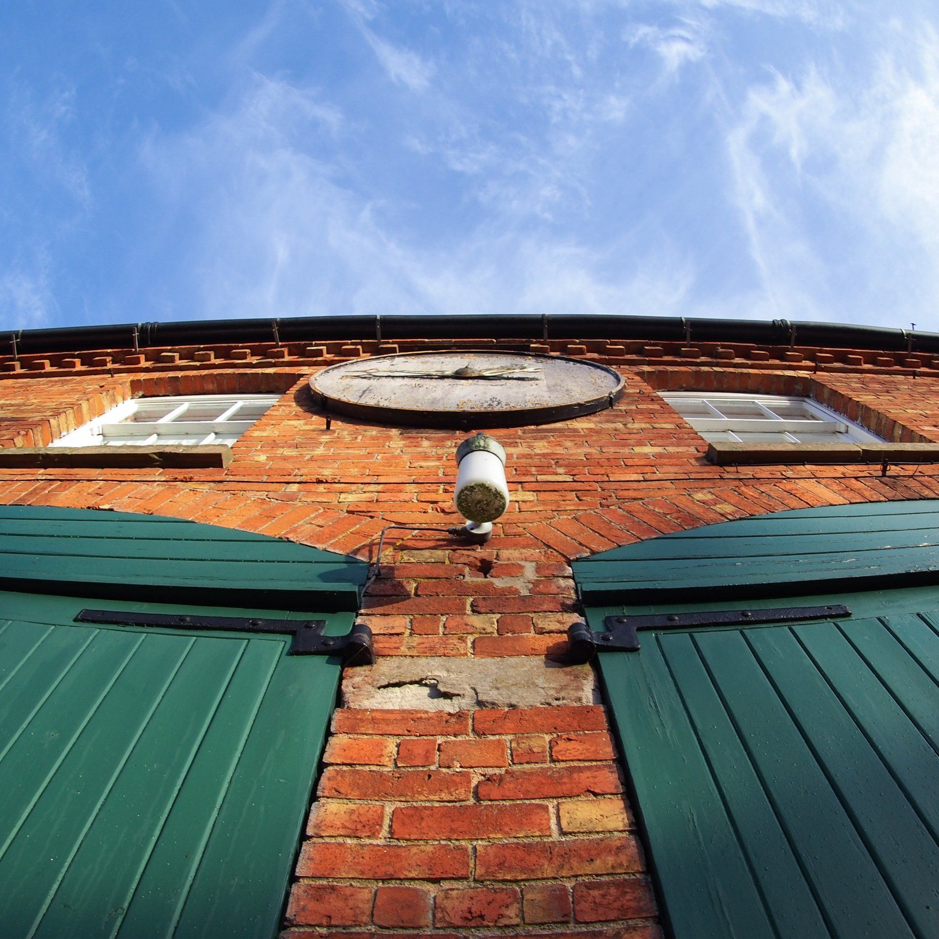 A brick building with green shutters and a clock on top