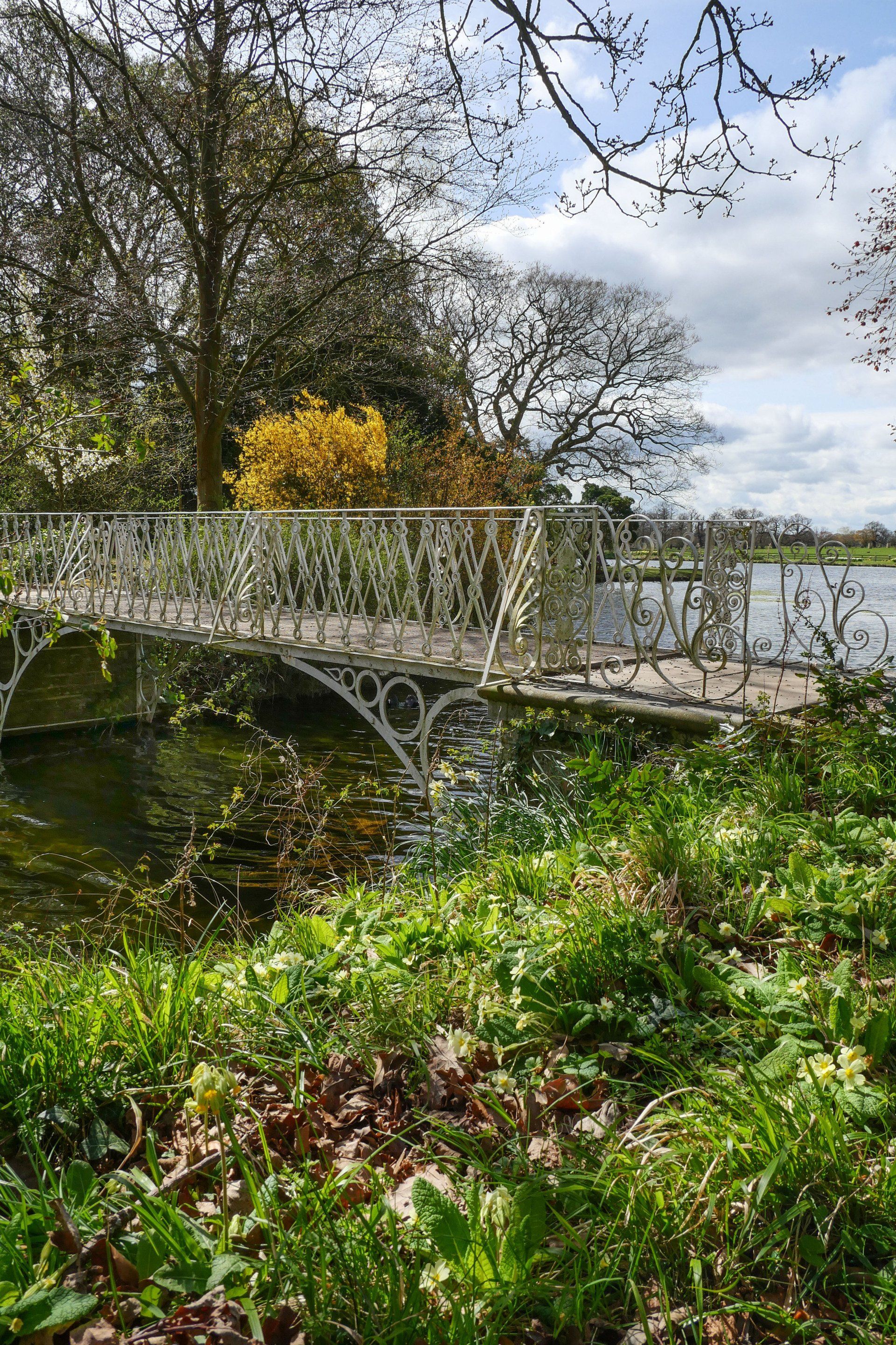 The attractive wrought-iron footbridge crosses the lake