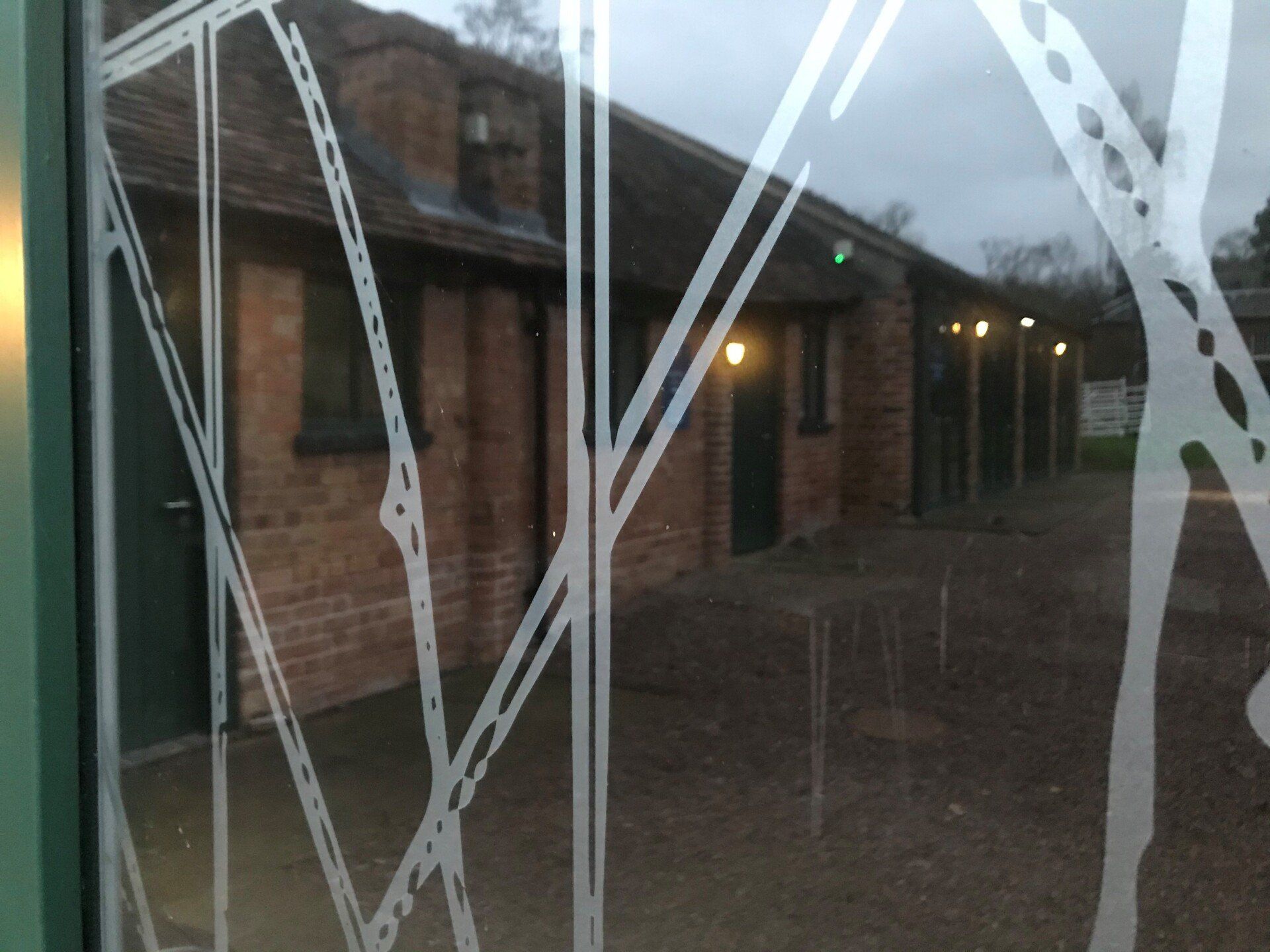 A brick building is reflected in a window with a design on it.