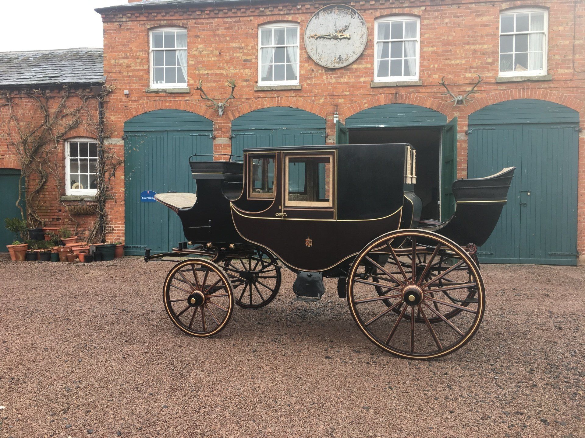 A horse drawn carriage is parked in front of a brick building.