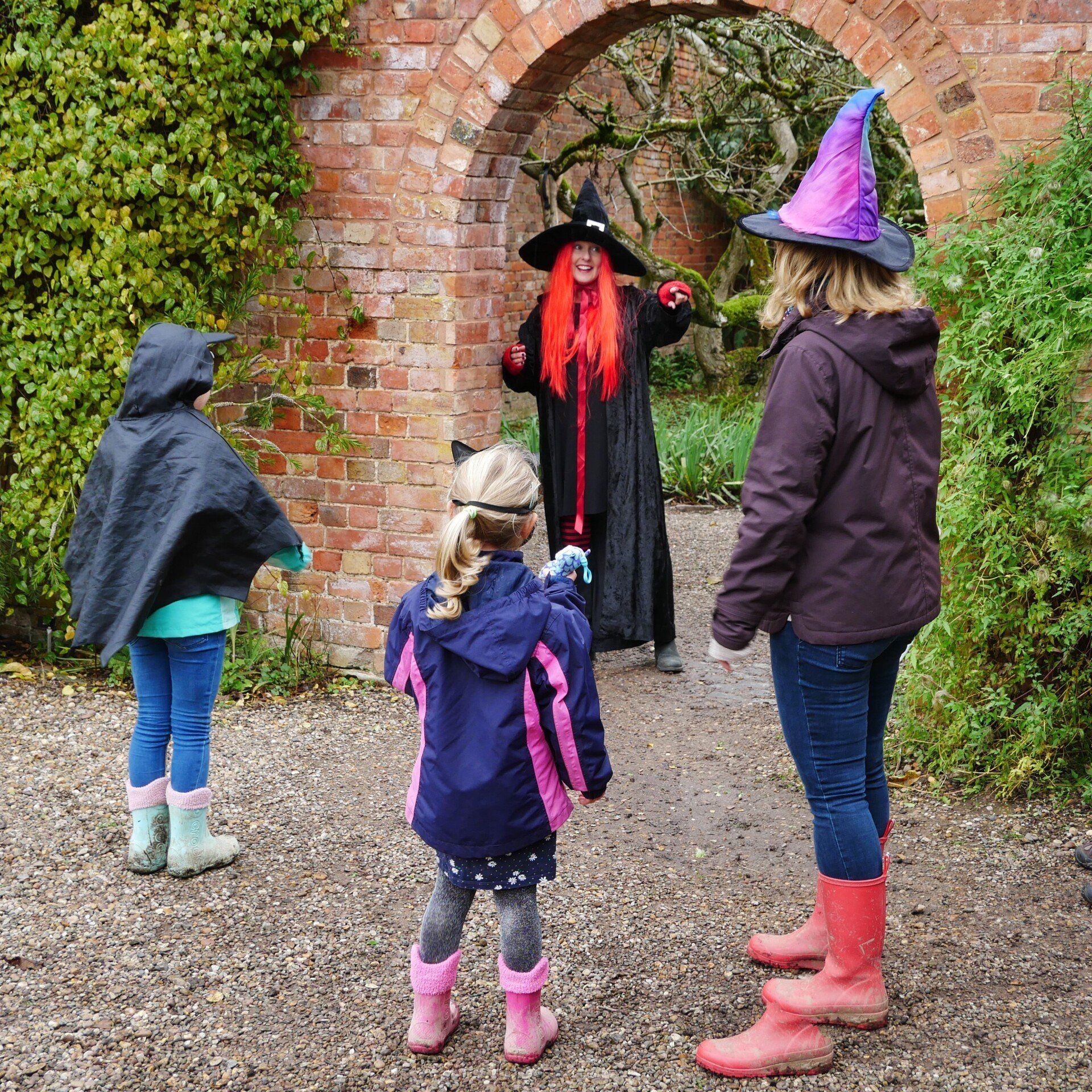 A woman in a witch costume is talking to two little girls at the halloween event
