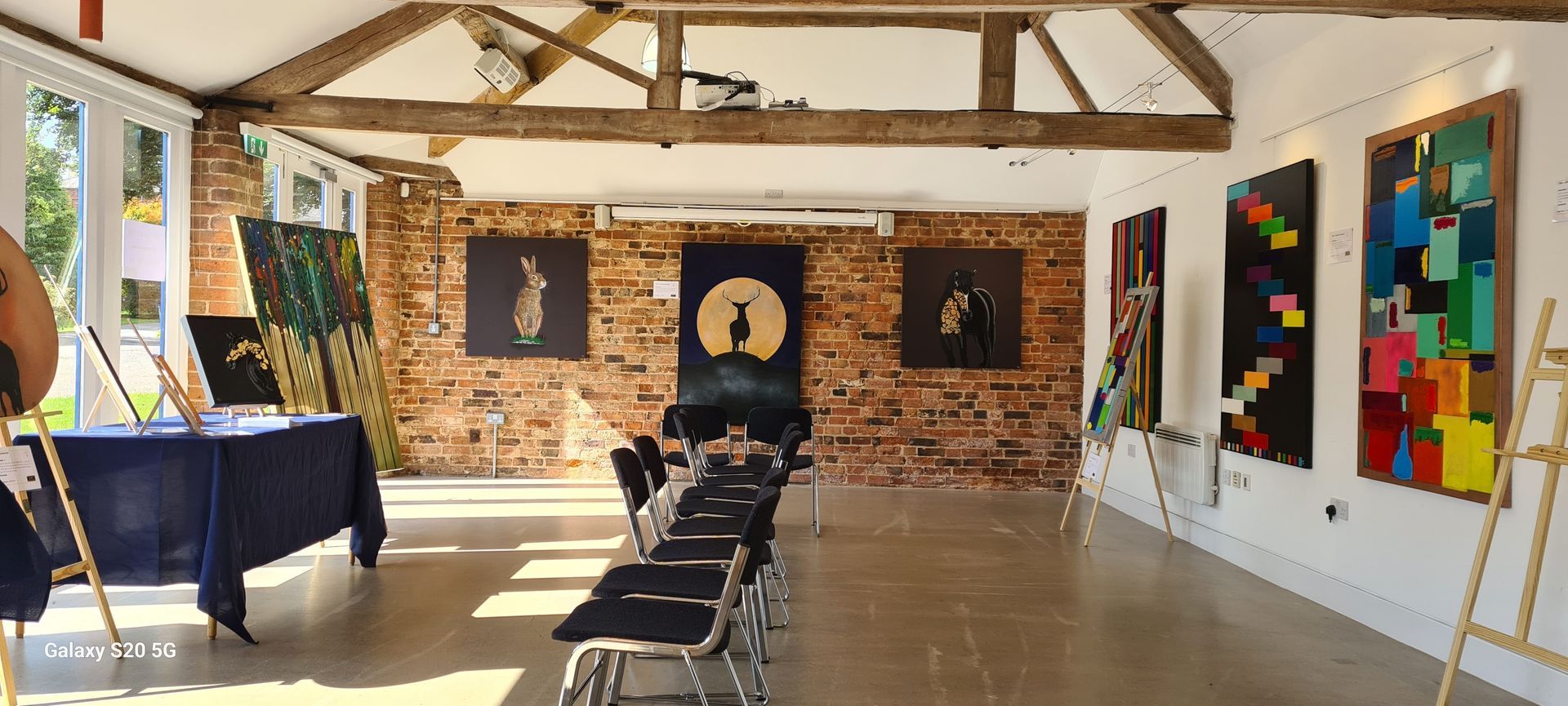 A large room with a table and chairs and paintings on the wall.