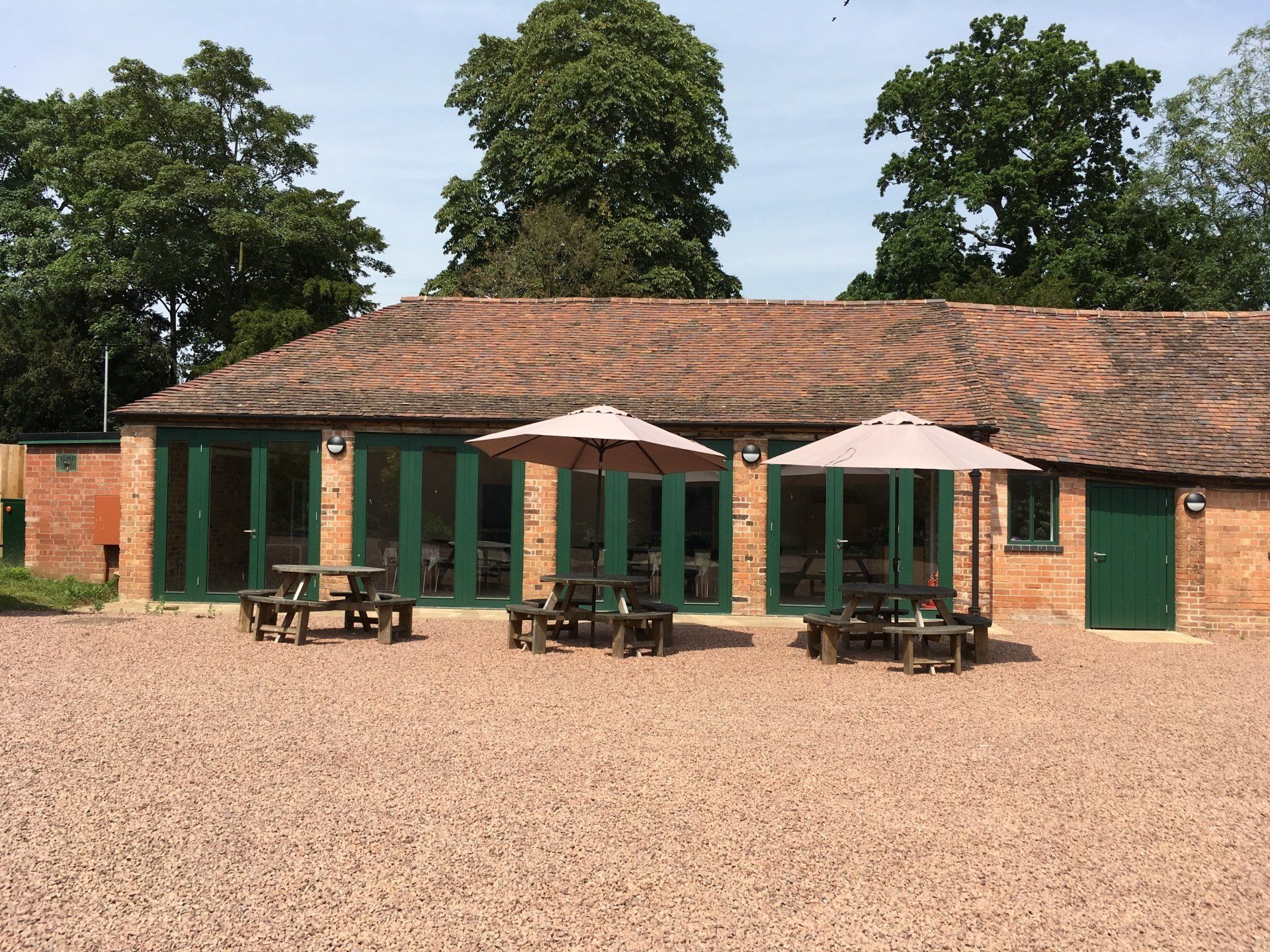 A large brick building with umbrellas and picnic tables in front of it