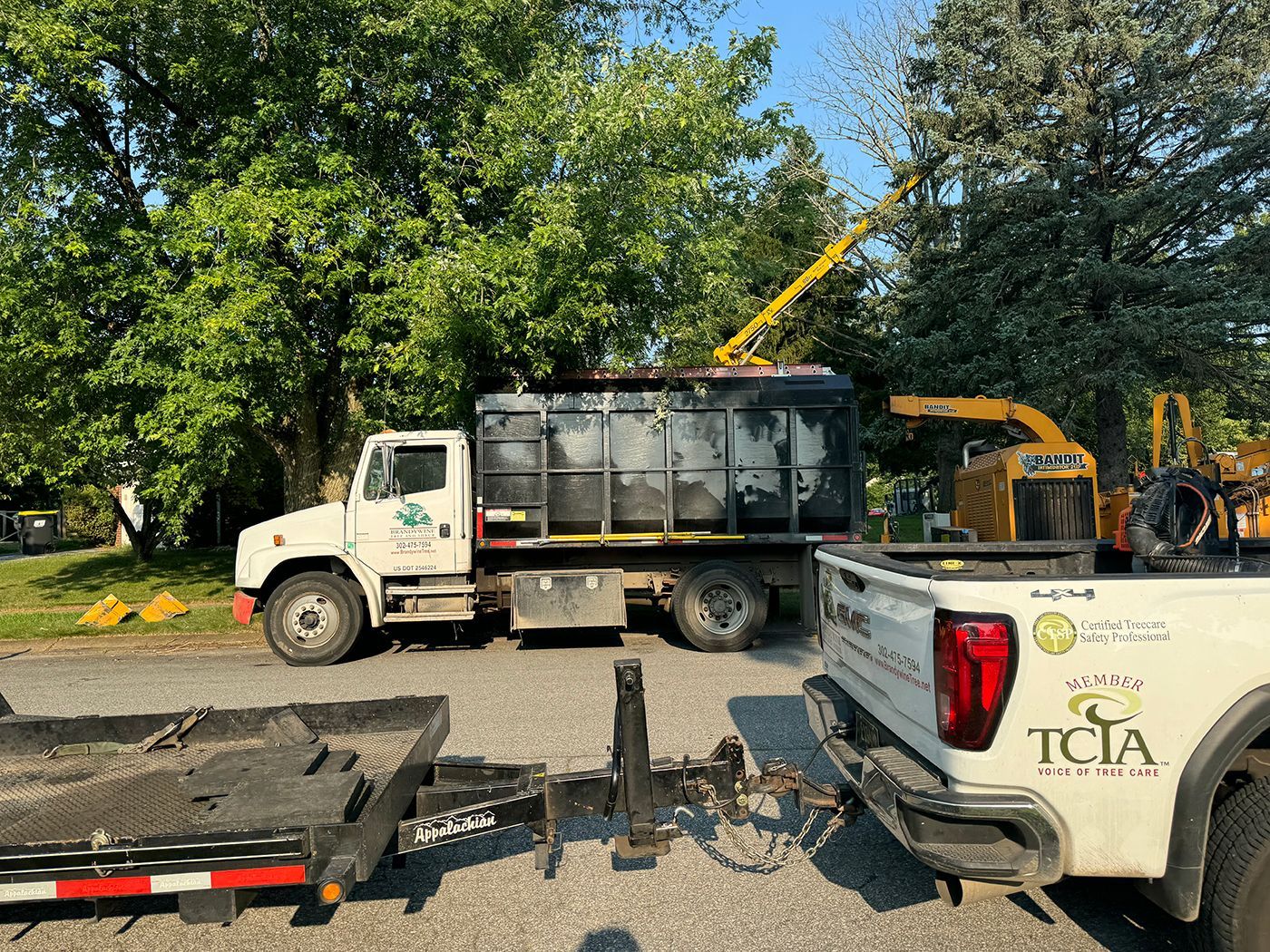 A white truck with a trailer attached to it is parked next to a dump truck.