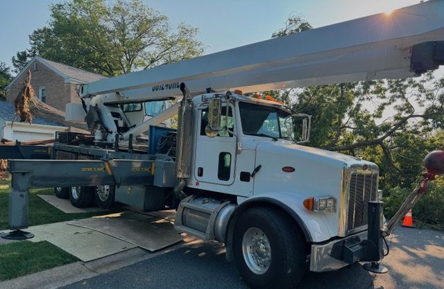 A white truck with a crane attached to it is parked on the side of the road.