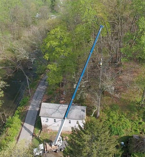 An aerial view of a house and a crane in the woods.