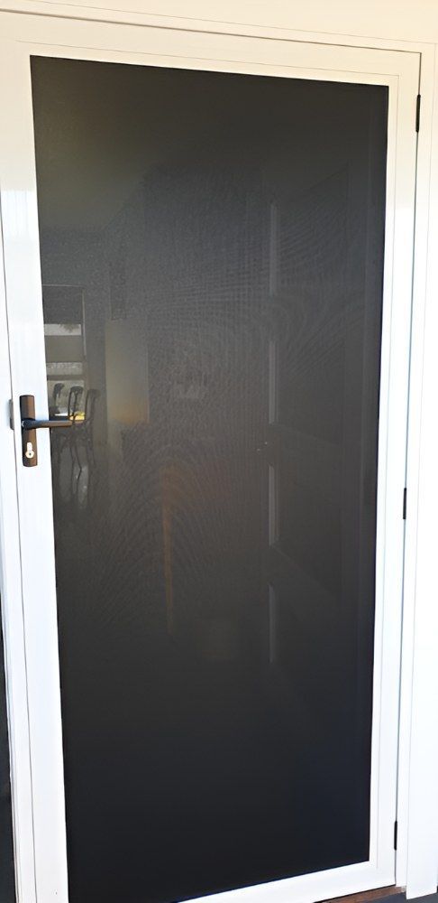 A Black Screen Door With a White Frame is Sitting in a Room — North Coast Screens & Repairs in Lennox Head, NSW