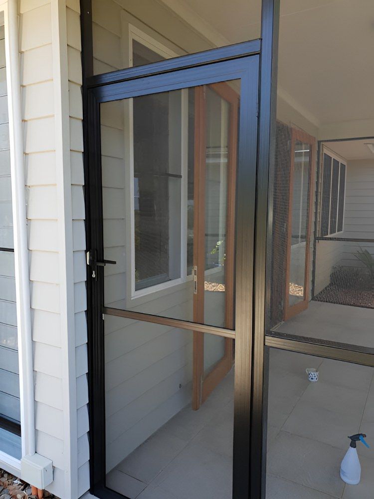 A Screen Door is Sitting on the Side of a House Next to a Window — North Coast Screens & Repairs in Goonellabah, NSW