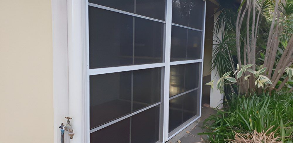 A White Screen Door is Sitting on the Side of a House — North Coast Screens & Repairs in Byron Bay, NSW