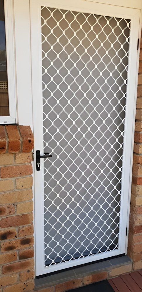 A White Door With a Mesh Screen on It is Sitting on a Brick Wall — North Coast Screens & Repairs in Alstonville, NSW