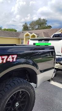 Black pickup truck parked in front of a yellow house, under a cloudy sky.