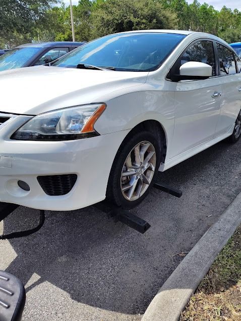 White car parked on ramps in a parking lot.