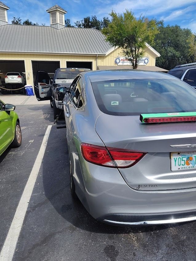 Silver Chrysler sedan parked outside a building with garage bays, blue sky above.
