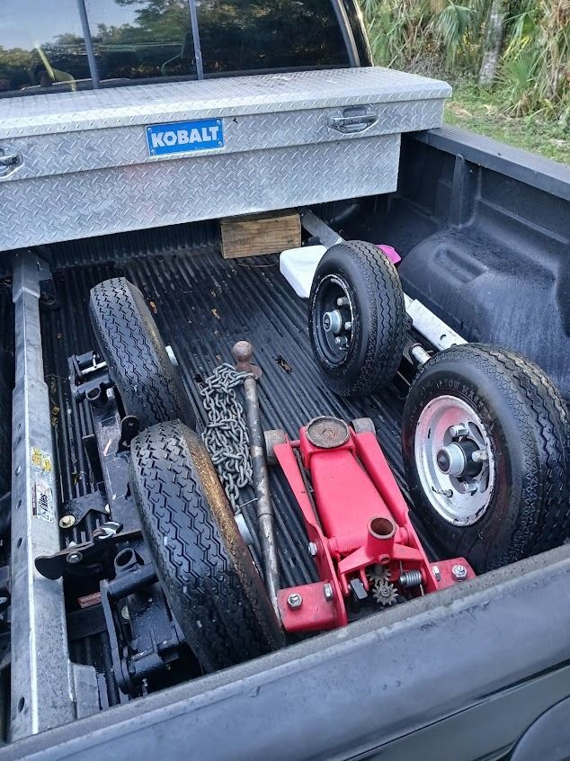 Truck bed with tires, jack, tool box, and equipment. Black bed, silver tool box, and tires.