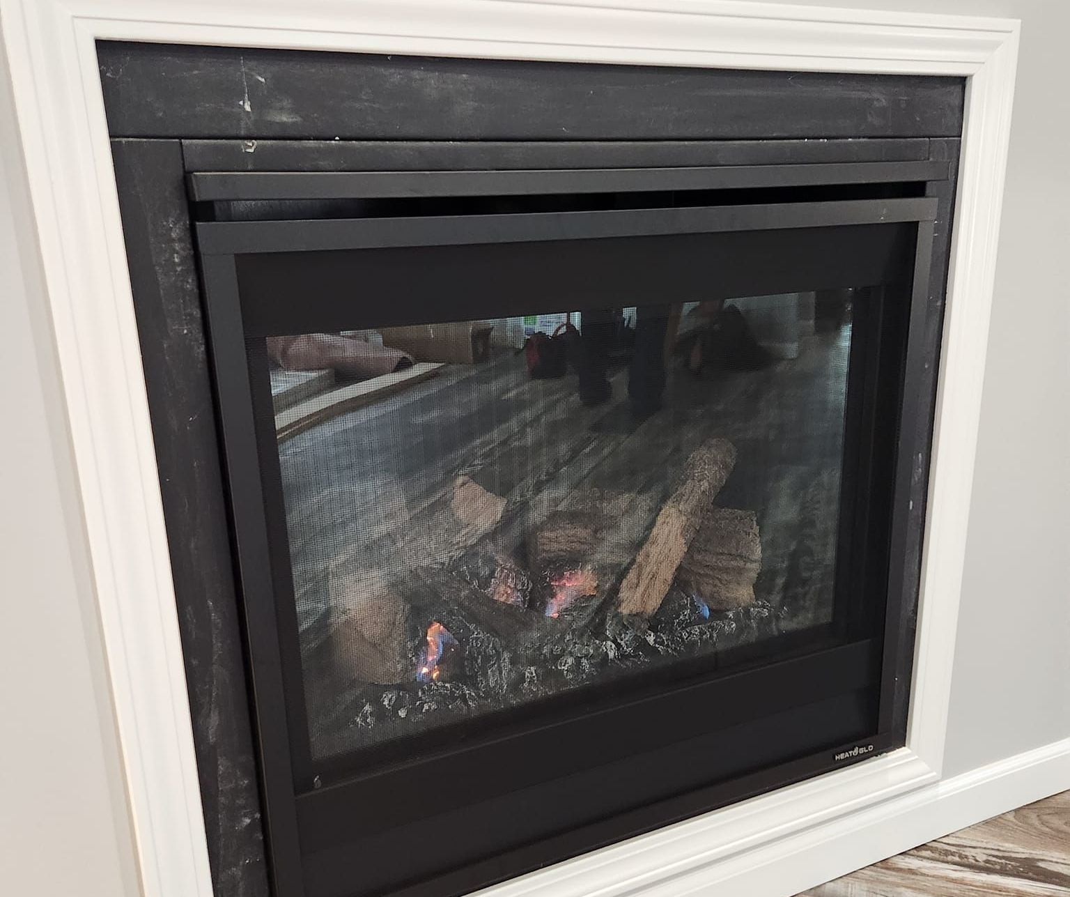 A modern fireplace with a glass door and a picture of a fire in it.