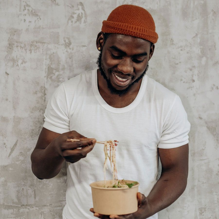 A man is eating noodles from a bowl with chopsticks.