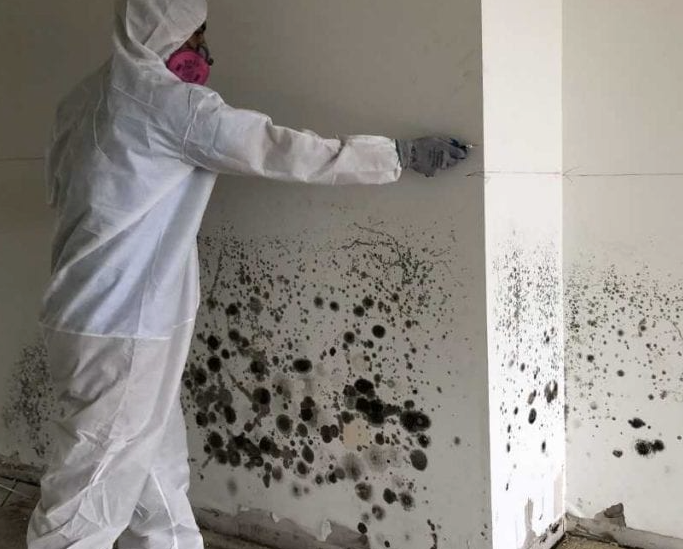 A woman is sitting on a couch coughing and holding her chest.