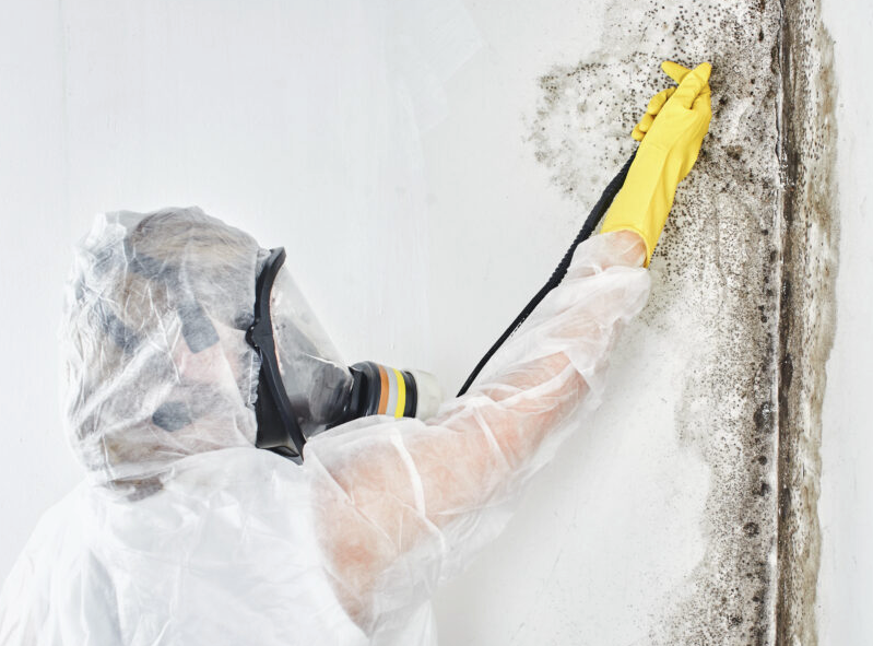 A woman is sitting on a couch coughing and holding her chest.