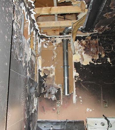A group of women are sitting at a long wooden table with laptops.