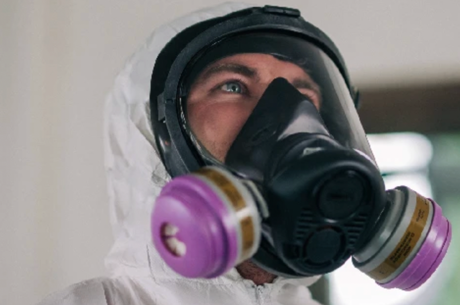 A puppy is sitting next to a puddle of pee on the floor.