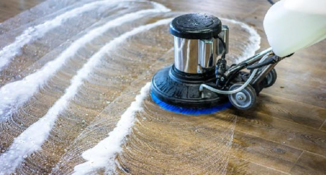 A man is cleaning the floor of an office with a mop.